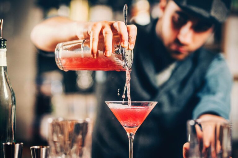 Ein Bartender gießt einen roten Cocktail in ein Glas