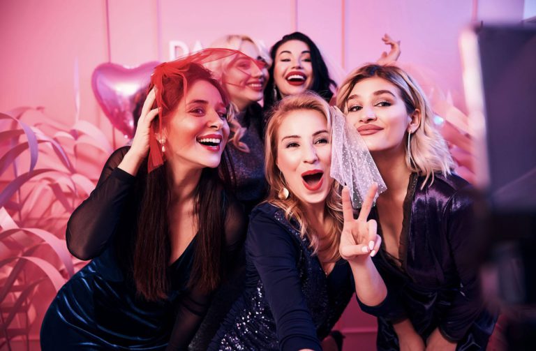 Fünf Frauen stehen verkleidet in einer Fotobox und haben Spaß.